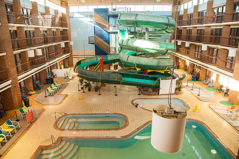 The indoor waterpark at Medicine Hat Lodge Resort in Alberta, showcasing winding green water slides, a pool, and a family-friendly leisure area within the resort.