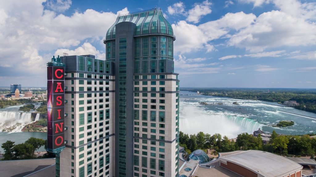 "Casino Niagara, Ontario: A modern and towering casino building overlooking the stunning Niagara Falls, with its iconic signage and picturesque surroundings under a bright daytime sky."