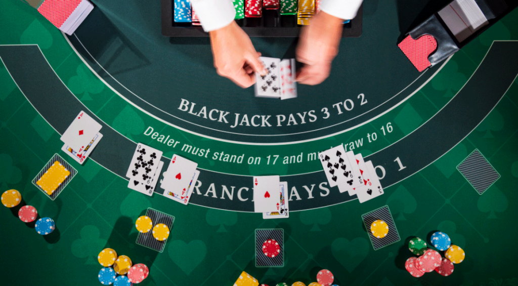 A blackjack table with a dealer dealing cards, surrounded by chips and hands of players engaged in the game in a casino