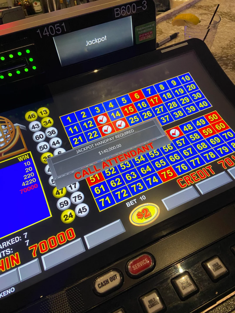 A casino Keno machine showing a $140,000 jackpot win with a highlighted "Call Attendant" message and selected numbers on the grid.