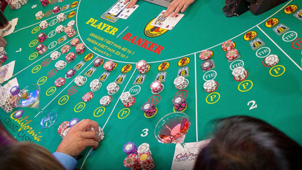 A crowded baccarat table with chips and cards, showing "Player" and "Banker" betting areas, a beginner-friendly game with straightforward rules in a casino