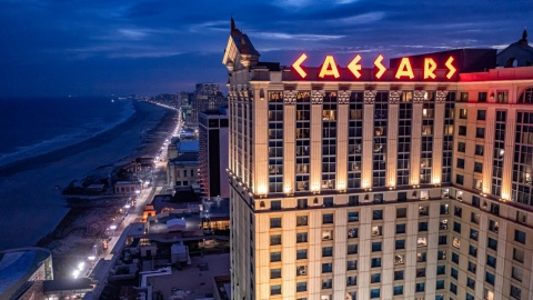 "Caesars Atlantic City illuminated at night, overlooking the Atlantic City Boardwalk and coastline."