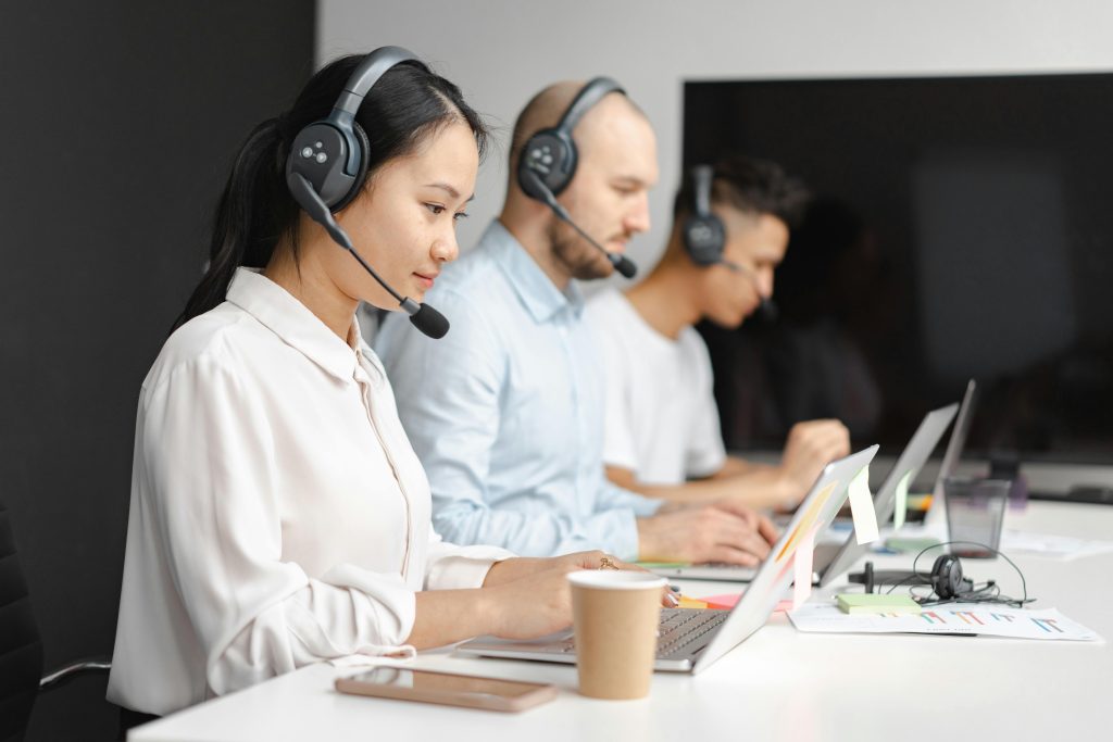 "Customer support team working on laptops with headsets."
