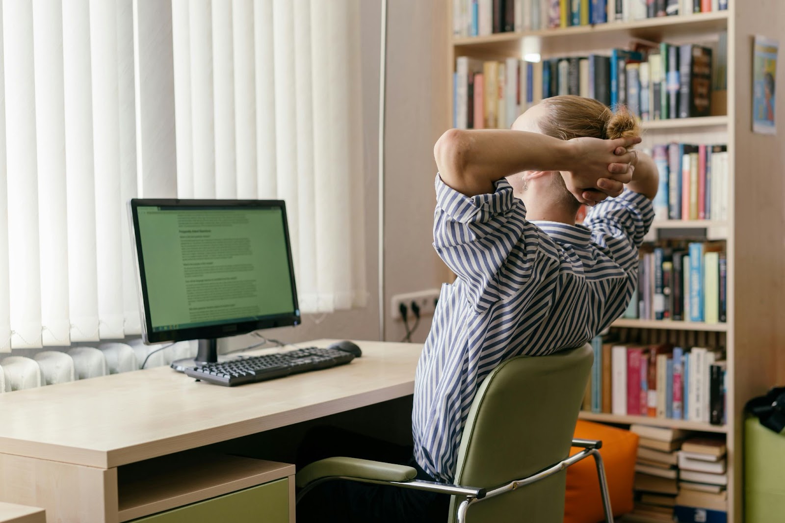 "Student exploring online fashion design courses on a computer, surrounded by books."