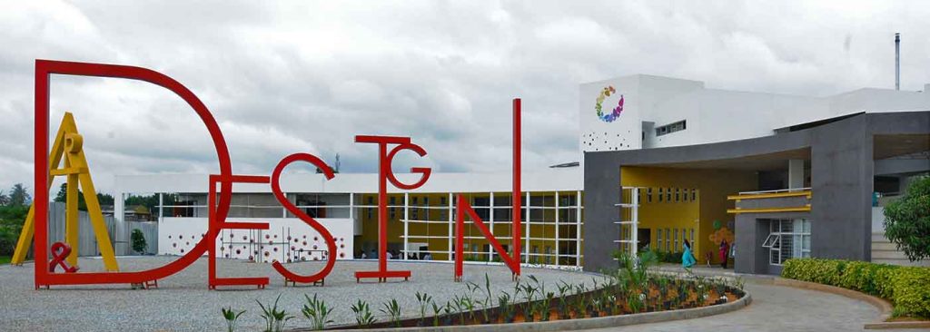 "The entrance of Vogue Institute of Art and Design in Bengaluru, featuring bold red 'DESIGN' lettering and a modern architectural structure. A premier institution for fashion, art, and design education."