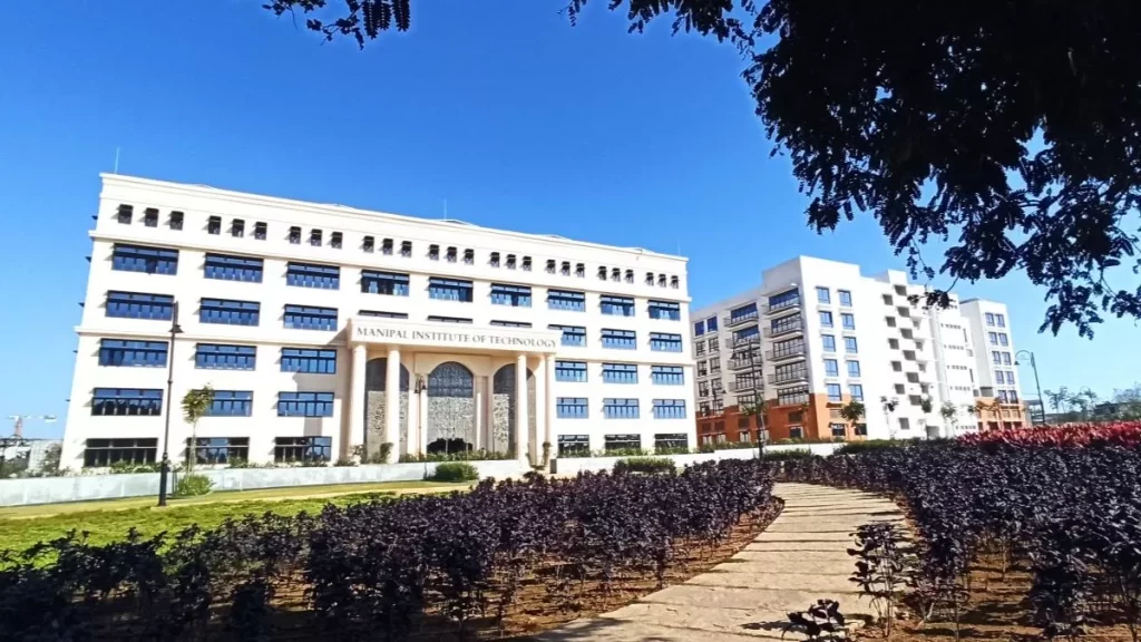 A picturesque view of the Srishti Manipal Institute campus, featuring a grand white building with lush greenery in the foreground, representing an inspiring space for aspiring fashion designers.